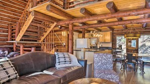A log cabin interior with a leather sofa, a dining area, and a kitchen with wooden beams. - Classic Colorado Log Home w/ Mountain Views! (Florissant)