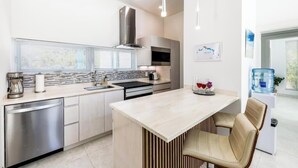 A modern kitchen with a dishwasher, sink, and a large island with seating. - Your tropical escape 2-bedroom villa with pool, 250 yards to Grace Bay Beach (The Bight Settlement)