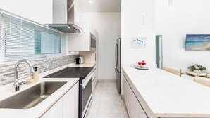 A modern kitchen with a built-in oven, a stainless steel sink, and a window with blinds. - Your tropical escape 2-bedroom villa with pool, 250 yards to Grace Bay Beach (The Bight Settlement)