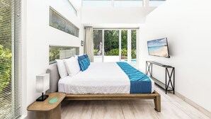 Ein modernes Schlafzimmer mit Bett, Nachttisch und Blick ins Grüne.