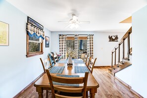 A dining area with a wooden table, chairs, and a ceiling fan.