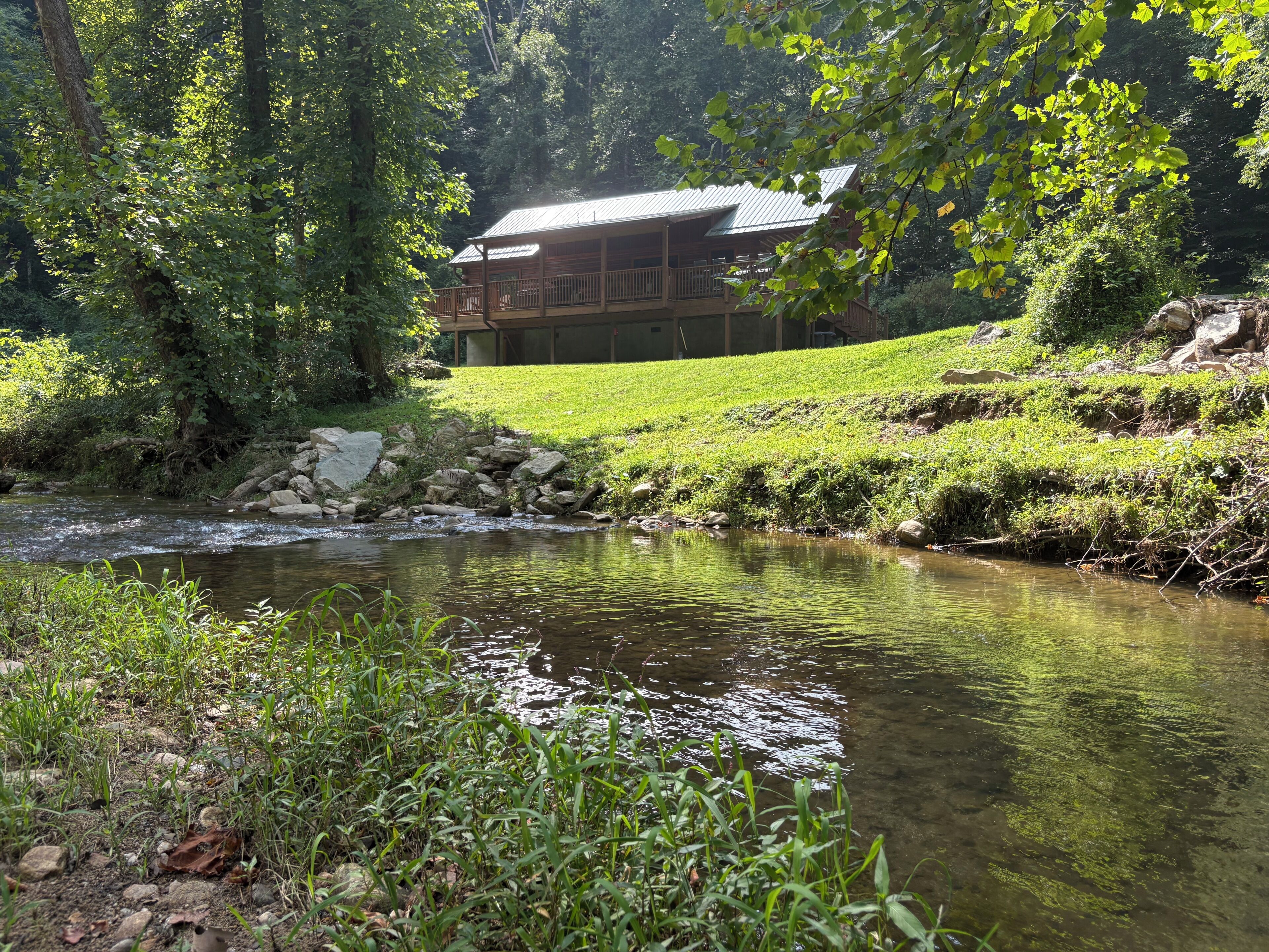 A riverside view with a wooden cabin and a grassy area.