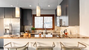 A modern kitchen with a central island, stainless steel appliances, pendant lighting, and bar stools. - Pandora by AvantStay | Modern Mountain Escape in Entrance of Bear Creek Trail (Telluride)