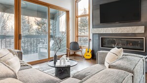 A modern living room with a fireplace, a large TV, and a view of a snowy landscape through large windows. - Pandora by AvantStay | Modern Mountain Escape in Entrance of Bear Creek Trail (Telluride)