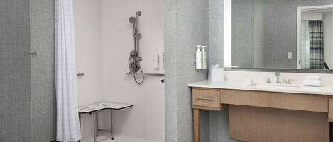 A modern bathroom with a shower, a sink, and a mirror.