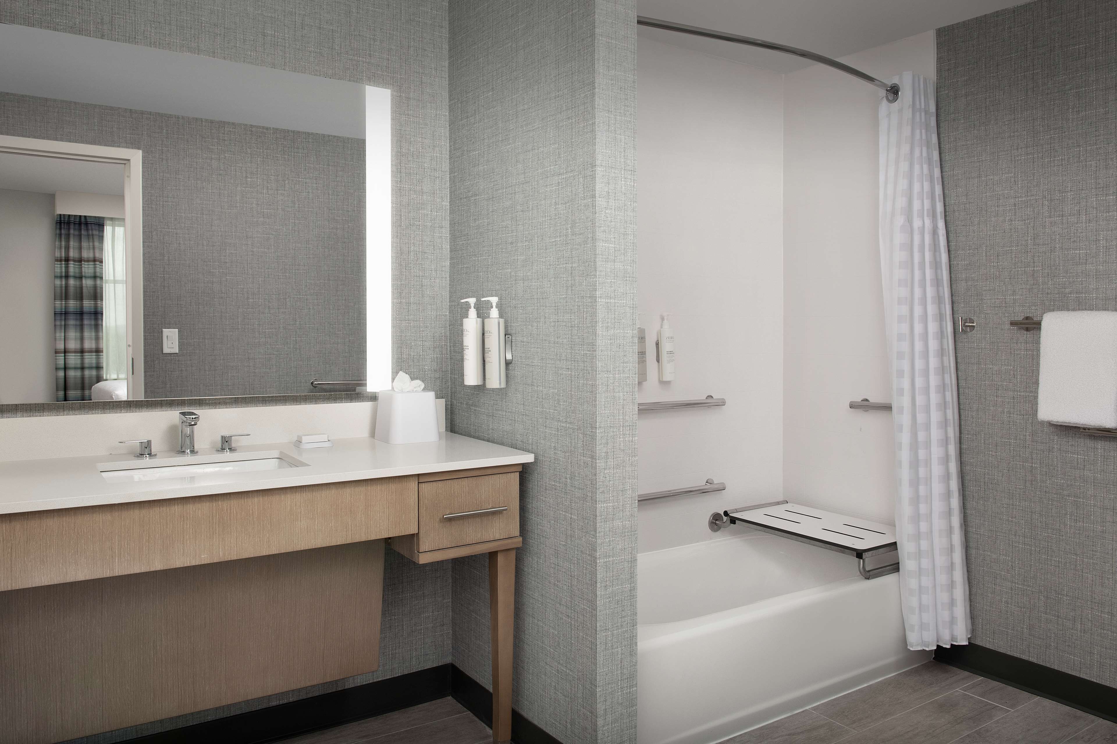A modern bathroom with a large mirror, a sink, a shower, and a bathtub.