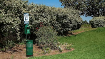 A green trash bin with a sign indicating it is for pet waste.