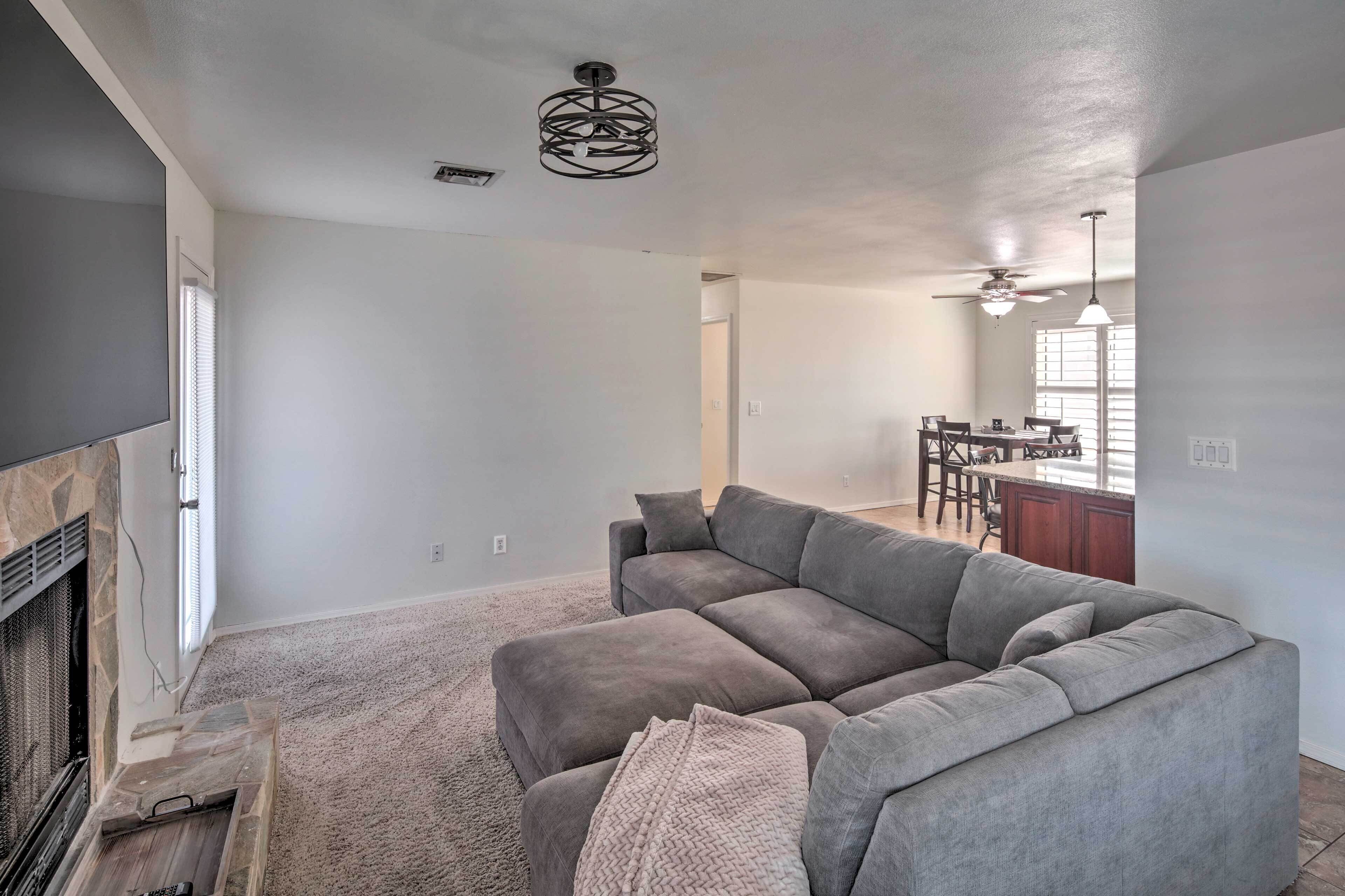 A living room with a gray sectional sofa, a fireplace, and a dining area in the background.