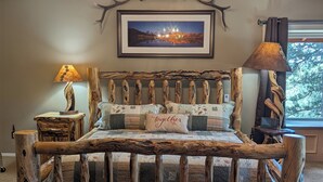 Ein rustikales Schlafzimmer mit einem hölzernen Bettgestell, einer Kristallleuchtre und einem gerahmten Bild an der Wand.