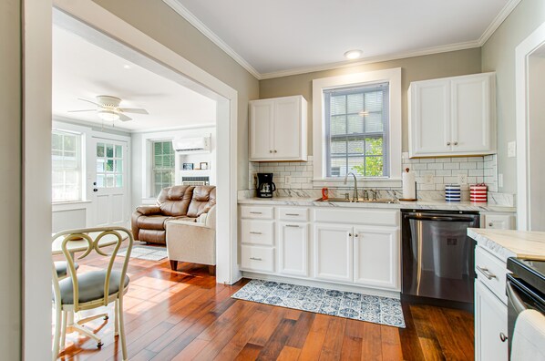 Kitchen features a large window, stainless steel dishwasher, and a patterned rug on the floor.
