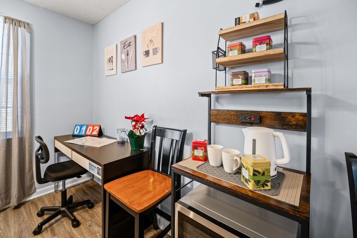 A small kitchenette with a coffee maker, mugs, and a shelf with jars.