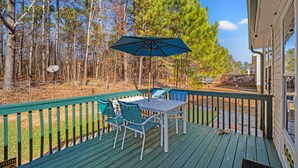 Eine Terrasse mit Tisch und Stühlen, umgeben von einer Holzbrüstung.