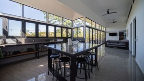 Una cucina moderna con isola centrale, sgabelli da bar e ampie finestre con vista sul verde.