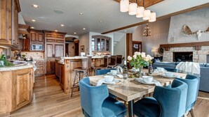 Una cocina amplia con armarios de madera, un comedor con sillas azules y una chimenea de piedra.