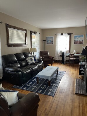 A living room with a black leather sofa, a wooden coffee table, and a dining area with a table and chairs.