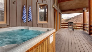 Un jacuzzi en una terraza de madera con paredes y ventanas de madera.