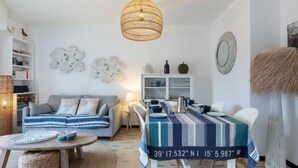 Un soggiorno moderno con un divano, un tavolo da pranzo con tovaglia a righe, una lampada a sospensione e decorazioni alle pareti.