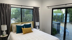Ein Schlafzimmer mit Bett, Vorhängen, einem Fenster und Blick ins Freie.