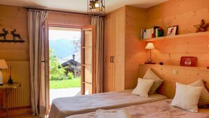 Una habitación acogedora con dos camas, un muro de madera, una mesita con una lámpara y vistas a zonas verdes.