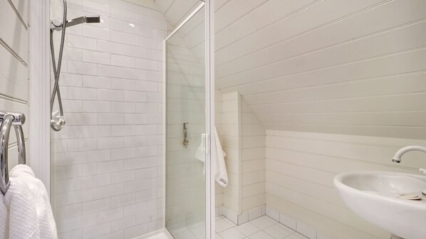 A modern bathroom with a glass shower enclosure, a white sink, and a towel rack. - Alpine Sadler Retreat (Merrijig)