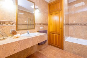 Ein Badezimmer mit Holztür, Waschbecken, Spiegel und Badewanne.