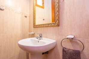 Une salle de bain avec un lavabo blanc, un miroir doté d’un cadre orné et un porte-serviette avec une serviette.