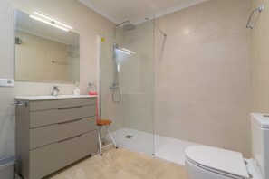 Une salle de bain moderne avec une douche à parois de verre, des toilettes blanches et un meuble-lavabo avec des tiroirs.