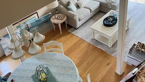 Uma sala de estar com sofá, mesa de centro e mesa de jantar com cadeiras.