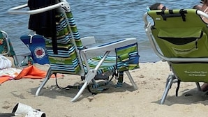 Ein Strand mit mehreren Liegestühlen und einem Sonnenschirm.