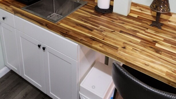 A kitchen with a wooden countertop, a sink, and a 'home' sign above the shelves. - Centrally Located Happy Haven (San Antonio)