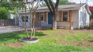 A single-story house with a front porch, a small tree in the front yard, and a clear sky. - Centrally Located Happy Haven (San Antonio)