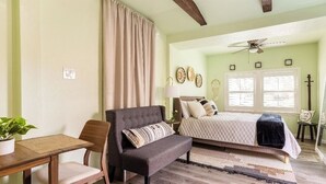 A bedroom with a bed, a bench, a table, and a ceiling fan. - Centrally Located Happy Haven (San Antonio)