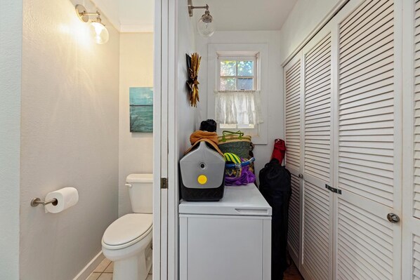 A compact bathroom with a toilet, a towel rack, and a window with a view.