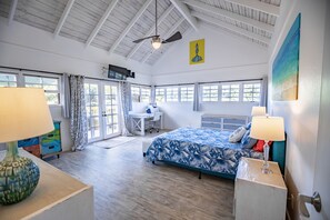 Une pièce spacieuse avec un grand lit, un bureau et un ventilateur de plafond.