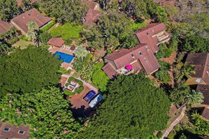 Vue aérienne d’un quartier résidentiel avec de nombreuses maisons, une piscine et une végétation luxuriante.