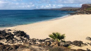 A beach with clear blue water, sandy shore, and rocky outcrops. - Molokai Oceanfront large beautiful home - Gorgeous secluded beaches out front! (Maunaloa)