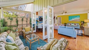 A spacious living area with a large sofa, a coffee table, and a dining area visible through an open door. - Molokai Oceanfront large beautiful home - Gorgeous secluded beaches out front! (Maunaloa)