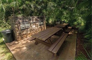 Une terrasse extérieure avec un mur en pierre, un barbecue et une table de pique-nique.