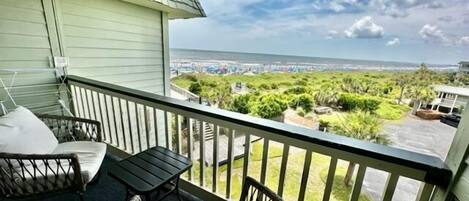 A balcony with a view of the ocean and a parking lot.