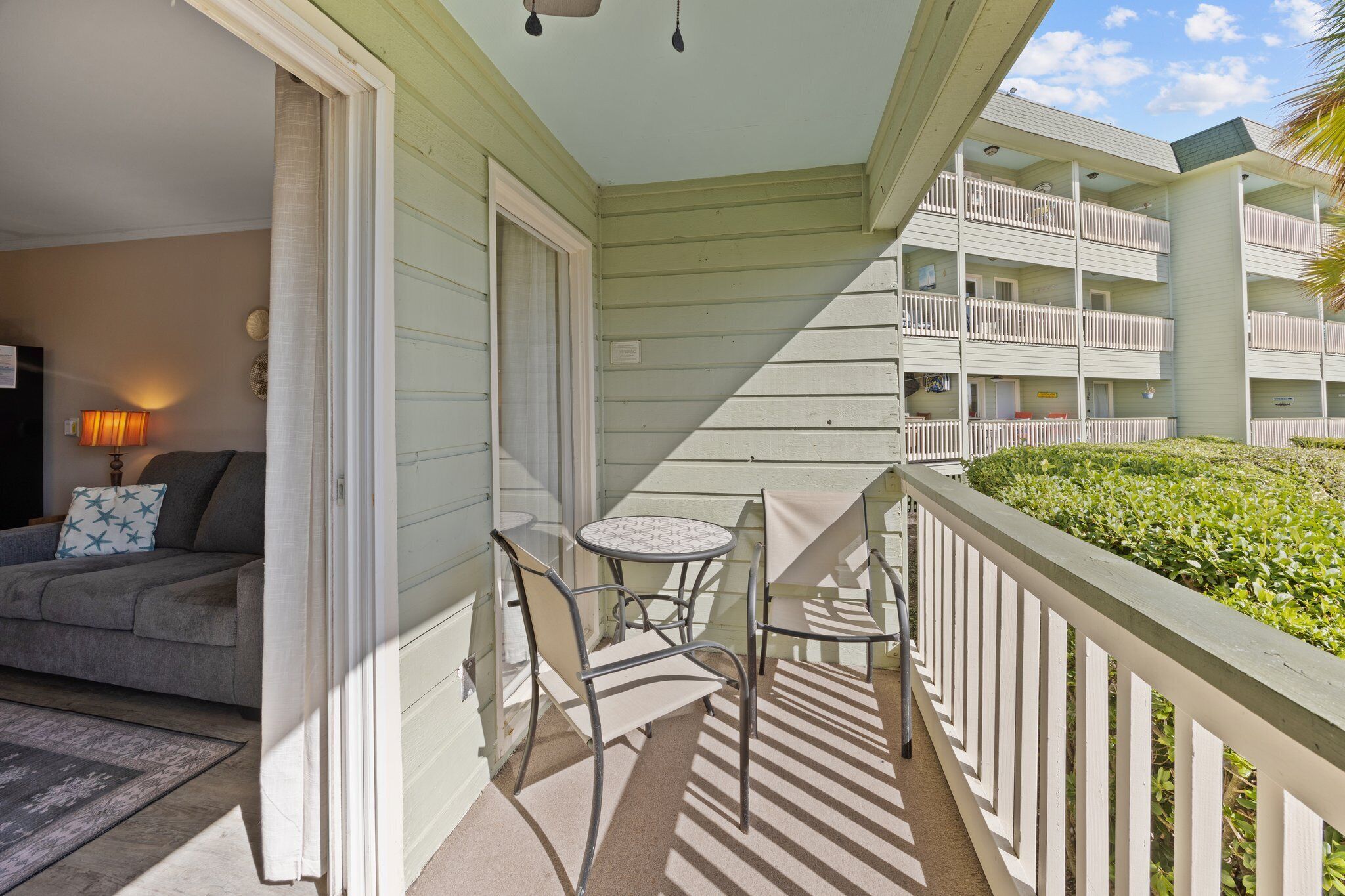 A balcony with a table and chairs, a sofa, and a view of adjacent buildings.