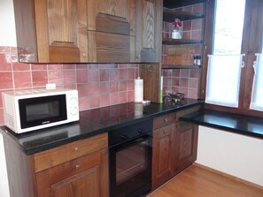 Una cocina con armarios de madera, microondas, estufa y ventana con vistas.