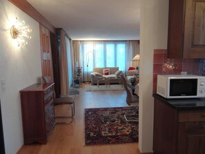 Una sala de estar con sofá, mesa de comedor y área de cocina con microondas.