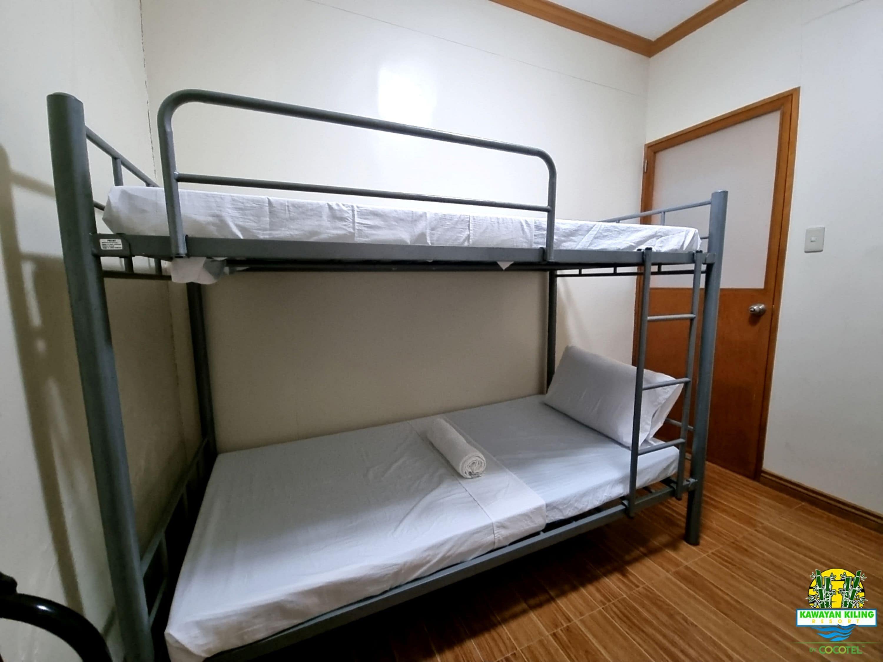 Habitación con literas, una puerta de madera y un interruptor de luz en la pared.