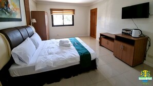Une chambre à coucher comprenant un lit, une télévision, une armoire et une fenêtre avec des stores.