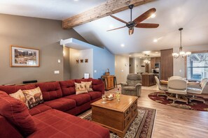 A spacious living room with a red sectional sofa, a wooden coffee table, and a dining area with a round table and chairs. - The Great Escape by Ruidoso Vacation Rentals (Ruidoso)