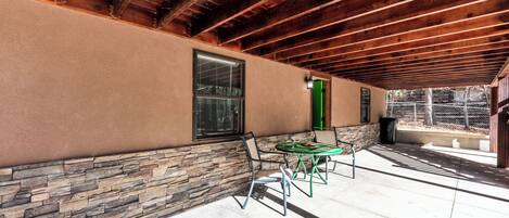 Un espace extérieur aménagé en terrasse, avec un mur en pierre, un plafond en bois et une table entourée de chaises.