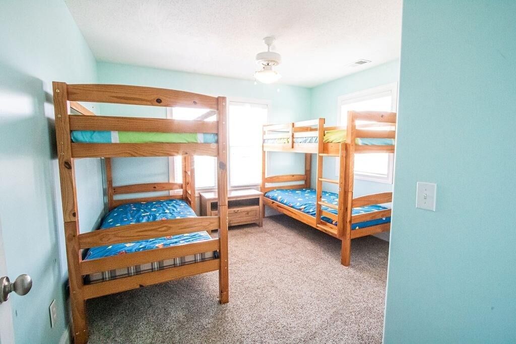 A room with bunk beds, carpeted floor, and a ceiling fan.