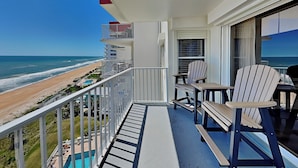 A balcony with a view of the beach and ocean.