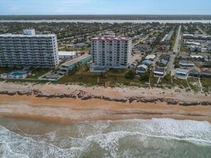 Vista aérea de una zona costera con un gran complejo hotelero, una playa y un puerto deportivo.