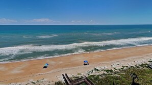 A beach with a wooden walkway leading to the shore, a sandy beach, and the ocean.